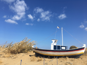 wooden boat on sand with blue sky and a few small clouds