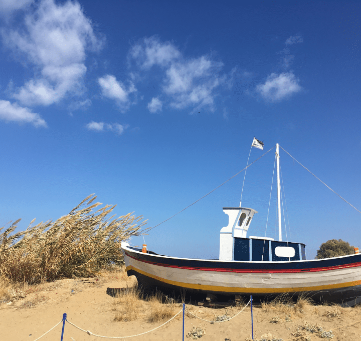 wooden boat on sand with blue sky and a few small clouds